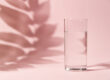 Half a glass of water on pink background