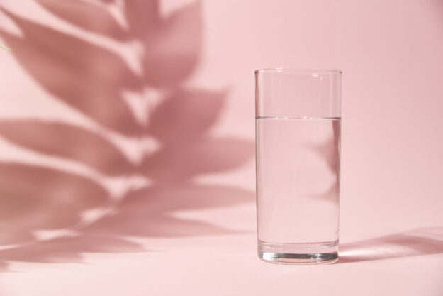 Half a glass of water on pink background