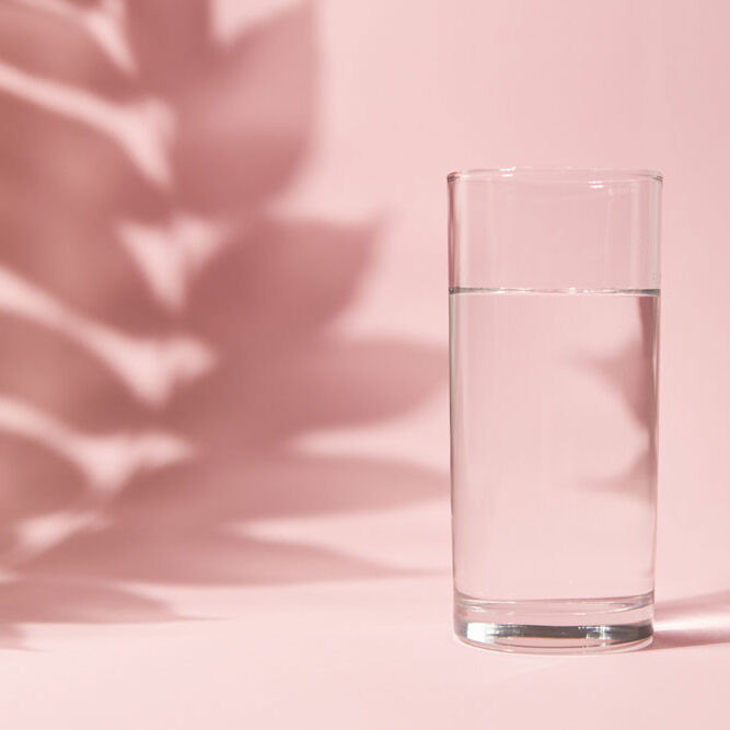 Half a glass of water on pink background